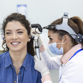 Hearing exam. Otolaryngologist doctor checking woman's ear using otoscope or auriscope at medical clinic.